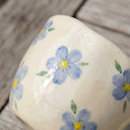 Koselig fin håndlaget kopp i keramikk med blå blomster på et bord detaljer. 