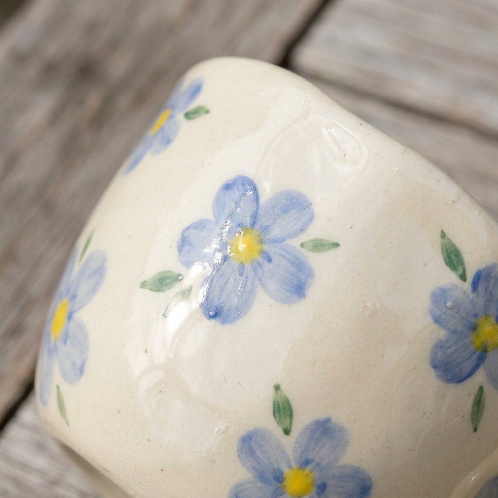 Koselig fin håndlaget kopp i keramikk med blå blomster på et bord detaljer. 