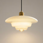 En pendellampe i glass med detaljer i et grått rom.