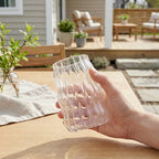 Hånd som holder iskaffeglass ute i sola. 