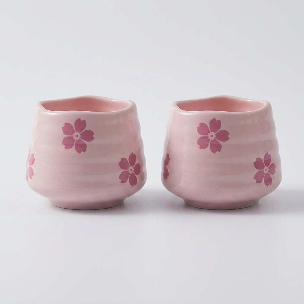 To fine kopper i rosa med rosa blomster laget i keramikk i et hvitt studio. 