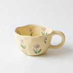 Koselig håndlaget kaffekopp i keramikk med blomster i et hvitt studio. 