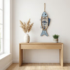 Veggdekor laget som en fisk i tre og tau iover en fin pult i et rom. 