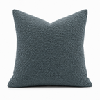 Blågrå putetrekk i bouclé  design i et hvitt studio. 