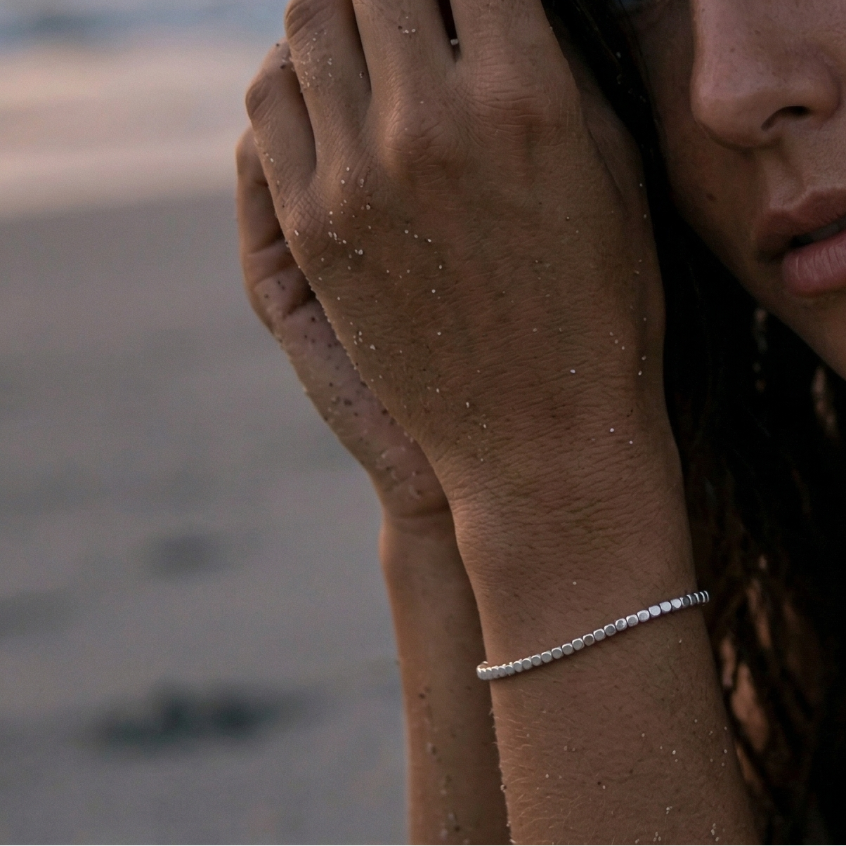 Jente på stranda med sterling sølv armbånd i sanden. 