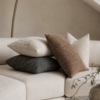 4 chenille putetrekk i nøytrale farger på en lys sofa. 