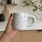 Hånd som holder en polkadott keramikkopp med prikker