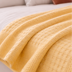 Detaljer av gult pledd over en seng. 