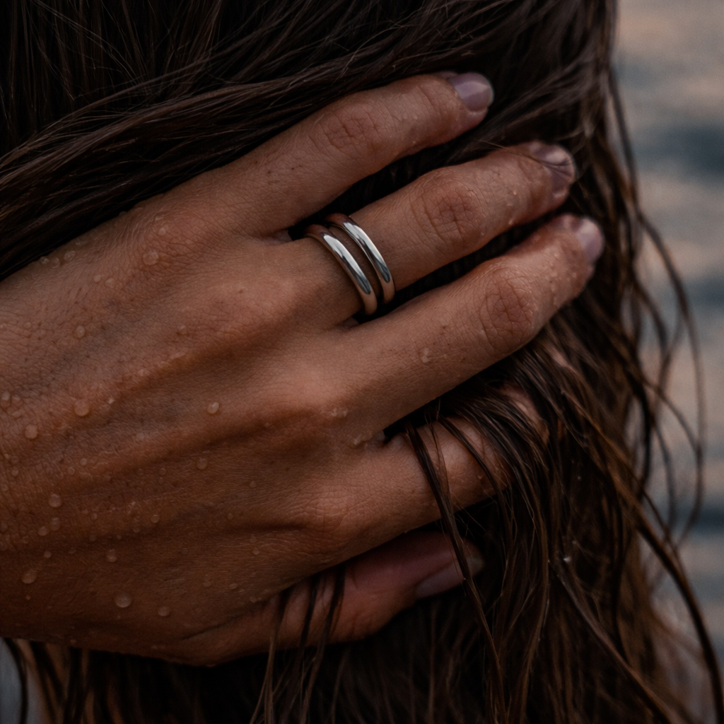 Sølv ring på en hand i vått hår.