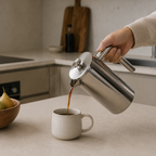 French press heller i kaffe i en kaffekopp på et kjøkken.