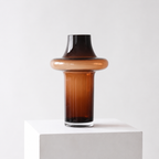 Unik formet glassvase i brunfarge i et hvitt studio.