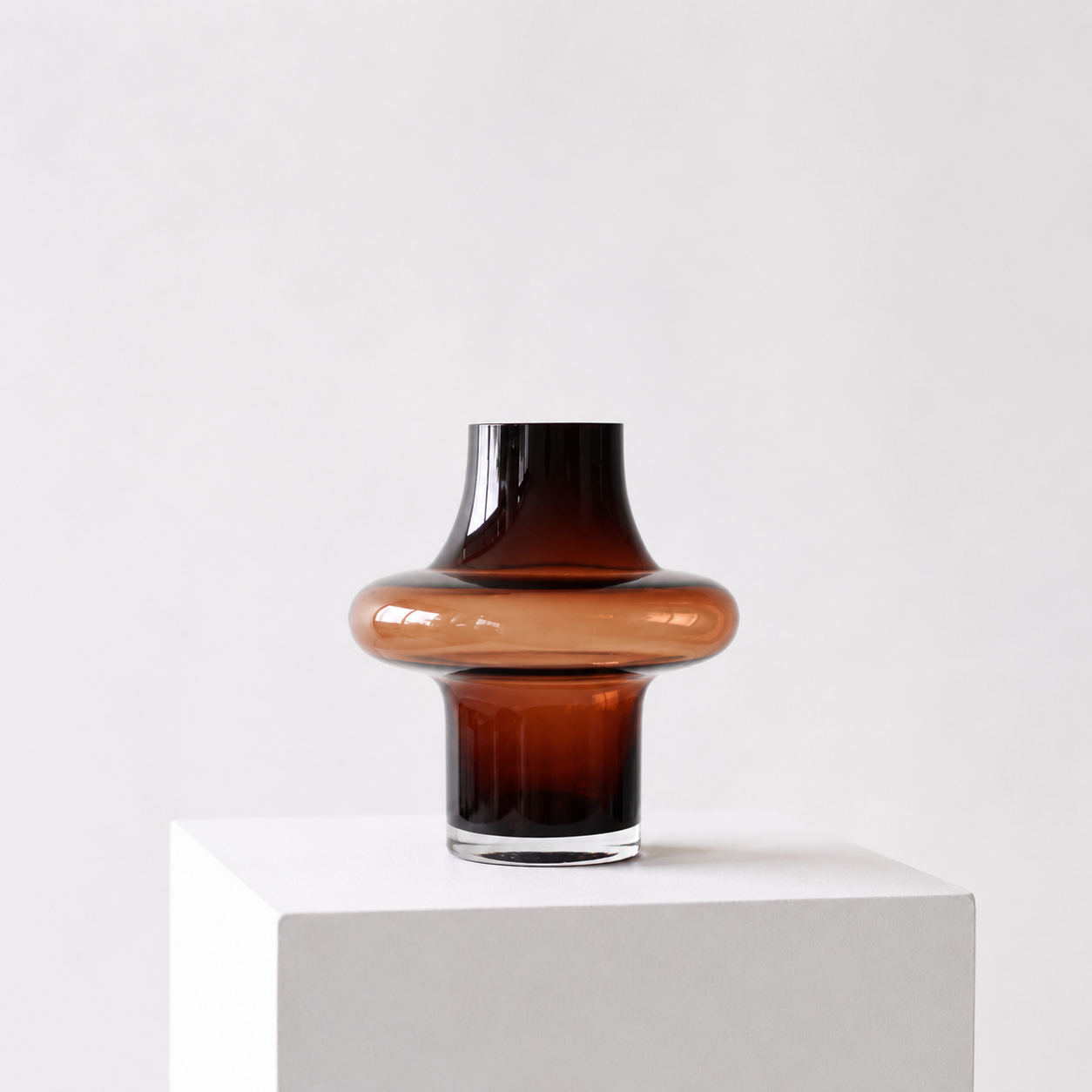 Unik glassvase i smoked brown farge i et hvitt studio. 