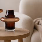 Liten glassvase i brun på et bord i en stue. 