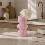 Rosa liten vase på et kjøkken med hvit blomst