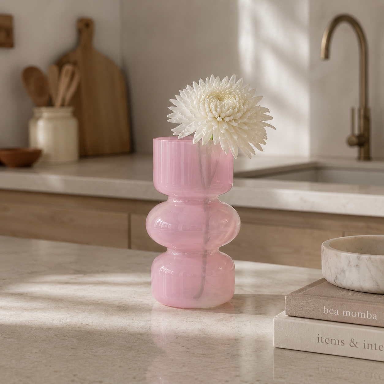 Rosa liten vase på et kjøkken med hvit blomst