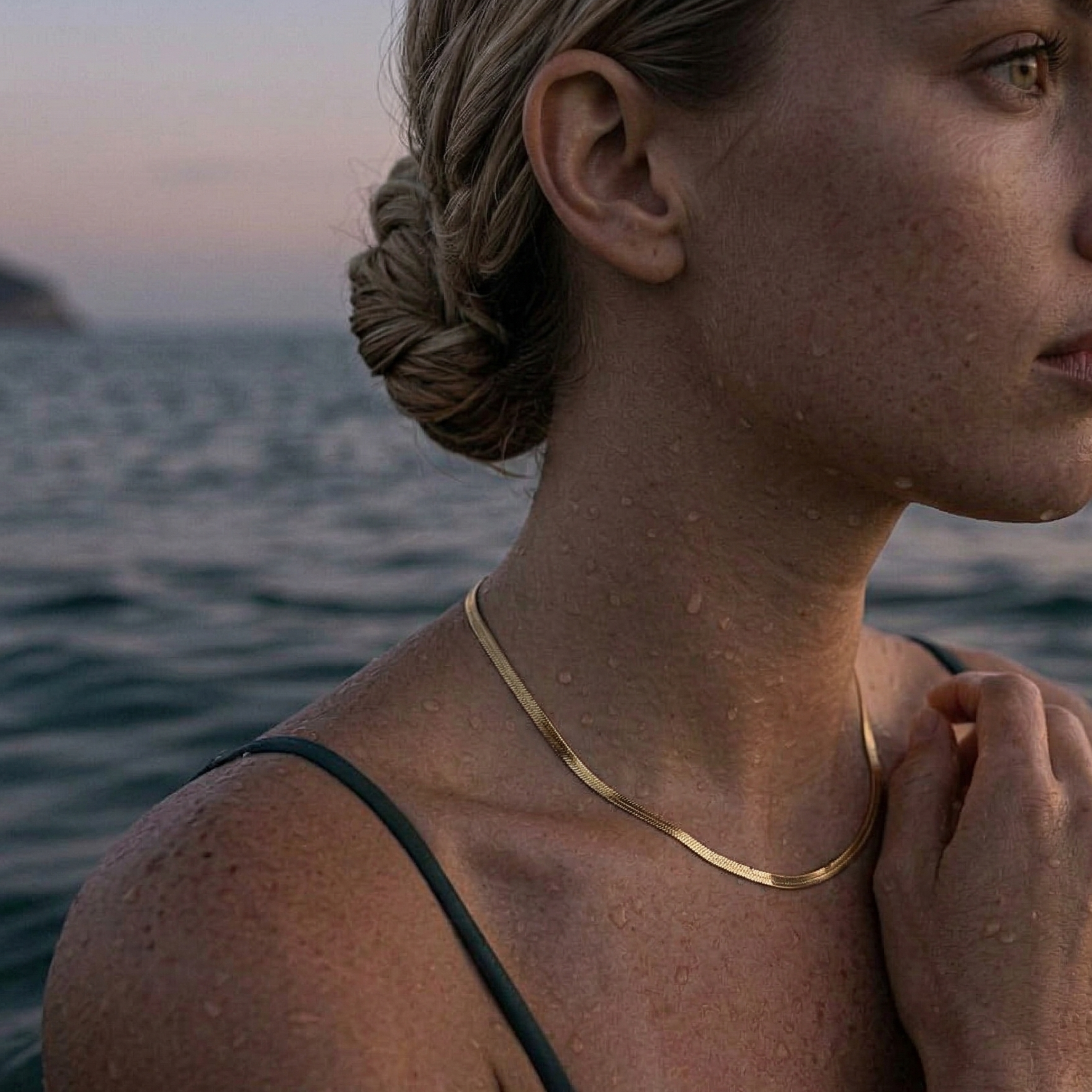 Herringbone kjede i gull smykke rundt halsen på en blond jente.