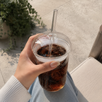 Glass med sugerør og lokk med cola i den.