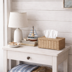 Et fint hvitt bord med en rattan tørkepapirholder på med papir inni. 