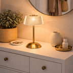 Lampe med glasskjerm på komode i gang med gullstolpe. 