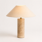 Hvitt studio med en beige lampe med steinlampekropp og stoff lampehode. 