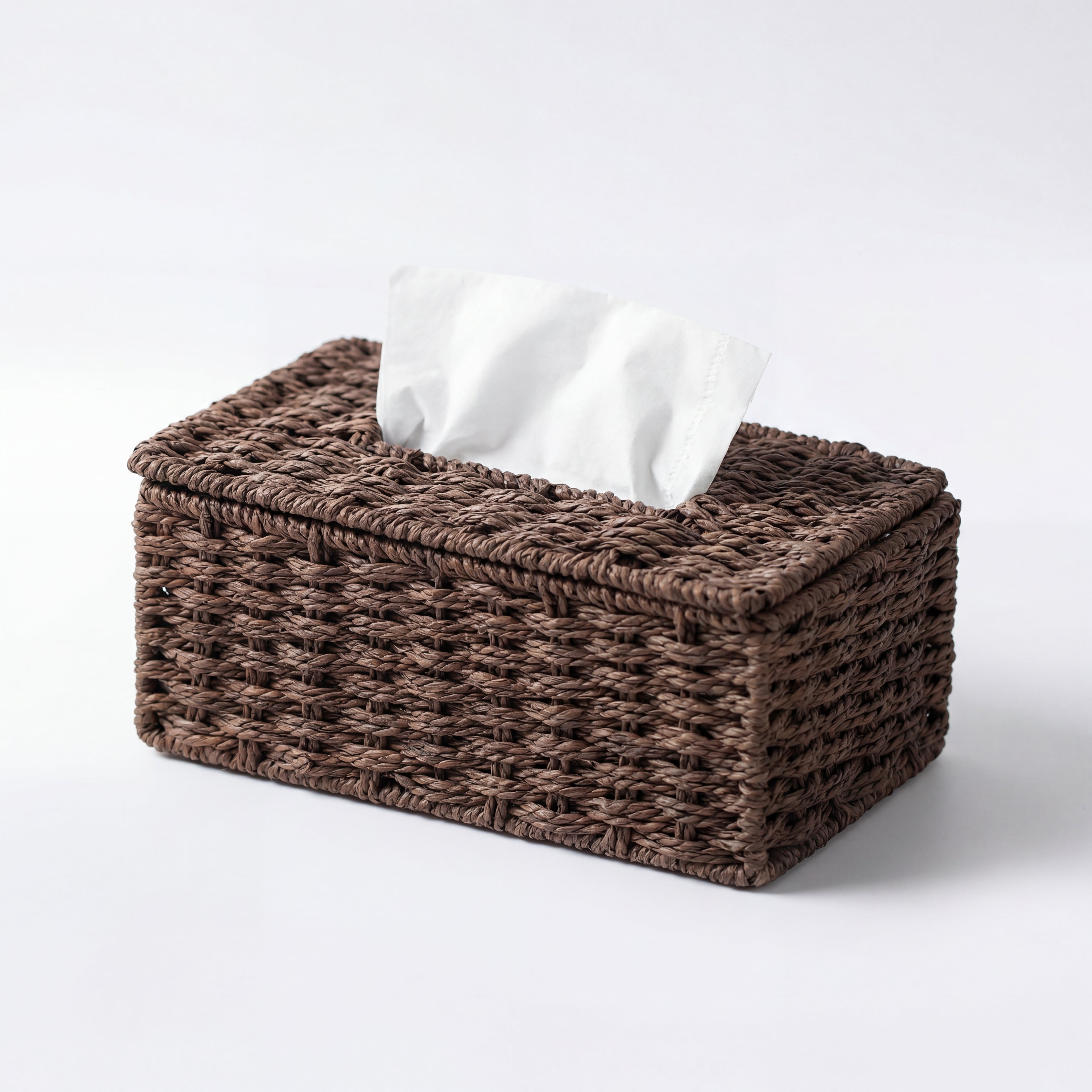 Tørkepapirholder med papir inni i en fin mørk rattan farge i et hvitt studio.