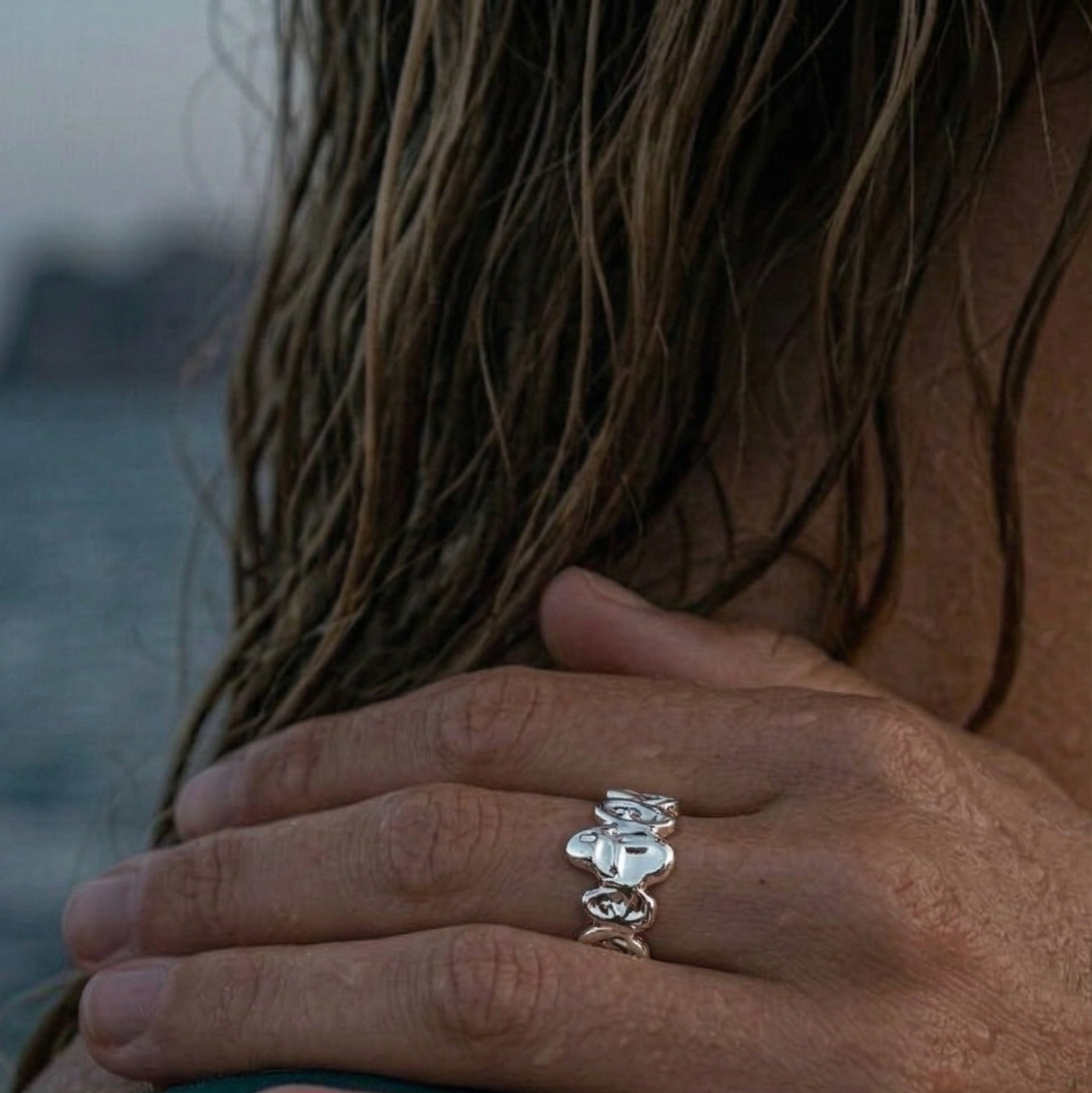 Jente med hånd på skulder med en sterling sølv ring i unikt design på seg.