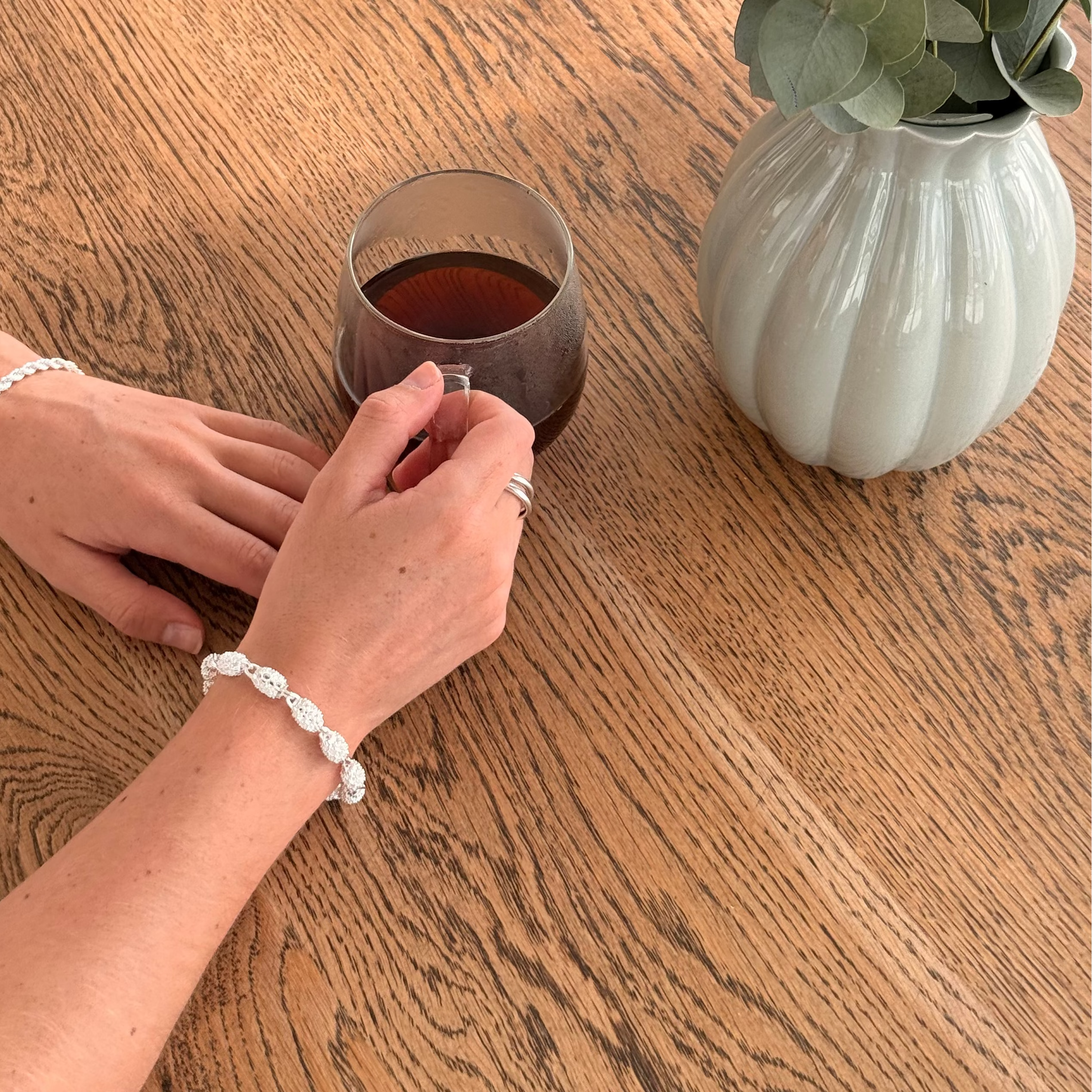 Armbånd i sølv detaljer på en håndmodell. 