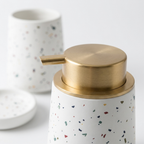 Detaljbilde av terrazzo-mønster på keramikk badesett med såpedispenser, tannbørsteholder og skål