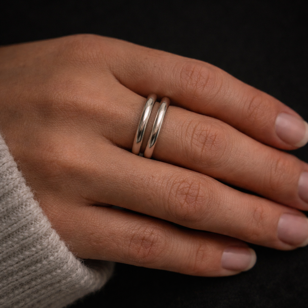 Sølv ring på en hånd i et sort studio.