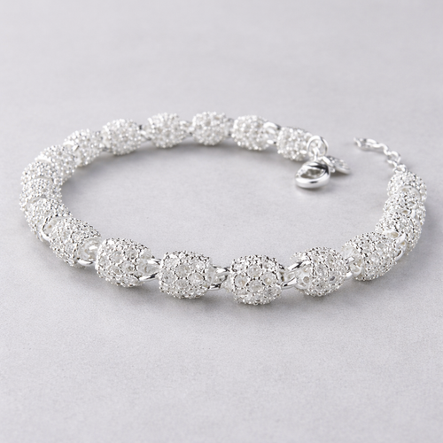 Sølv armbånd i et grått studio. 