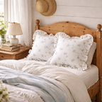 To søte hvite puter med volanger og sommerprint i en treseng. 