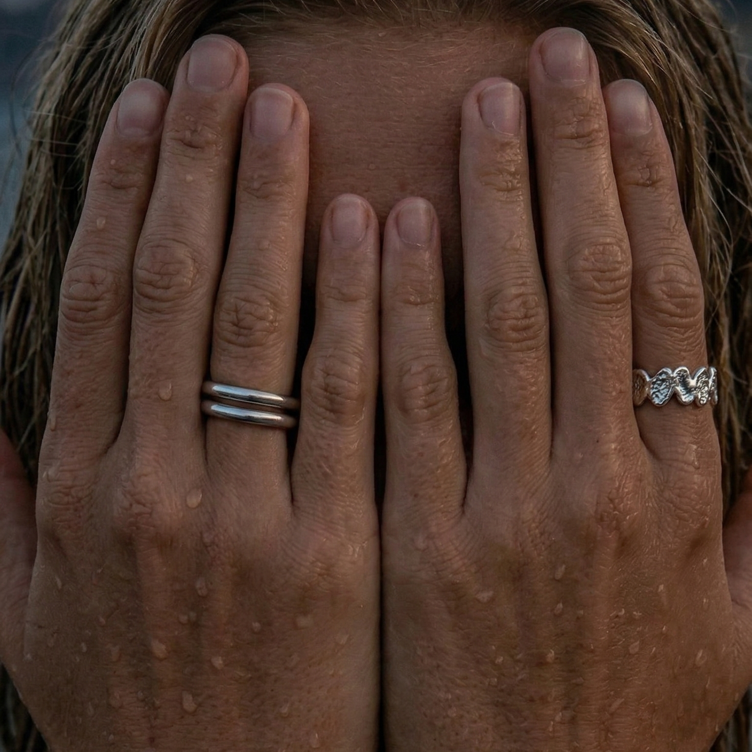 Jente med hendene forran ansiket med to fine sterling silver ringer på hendene. 