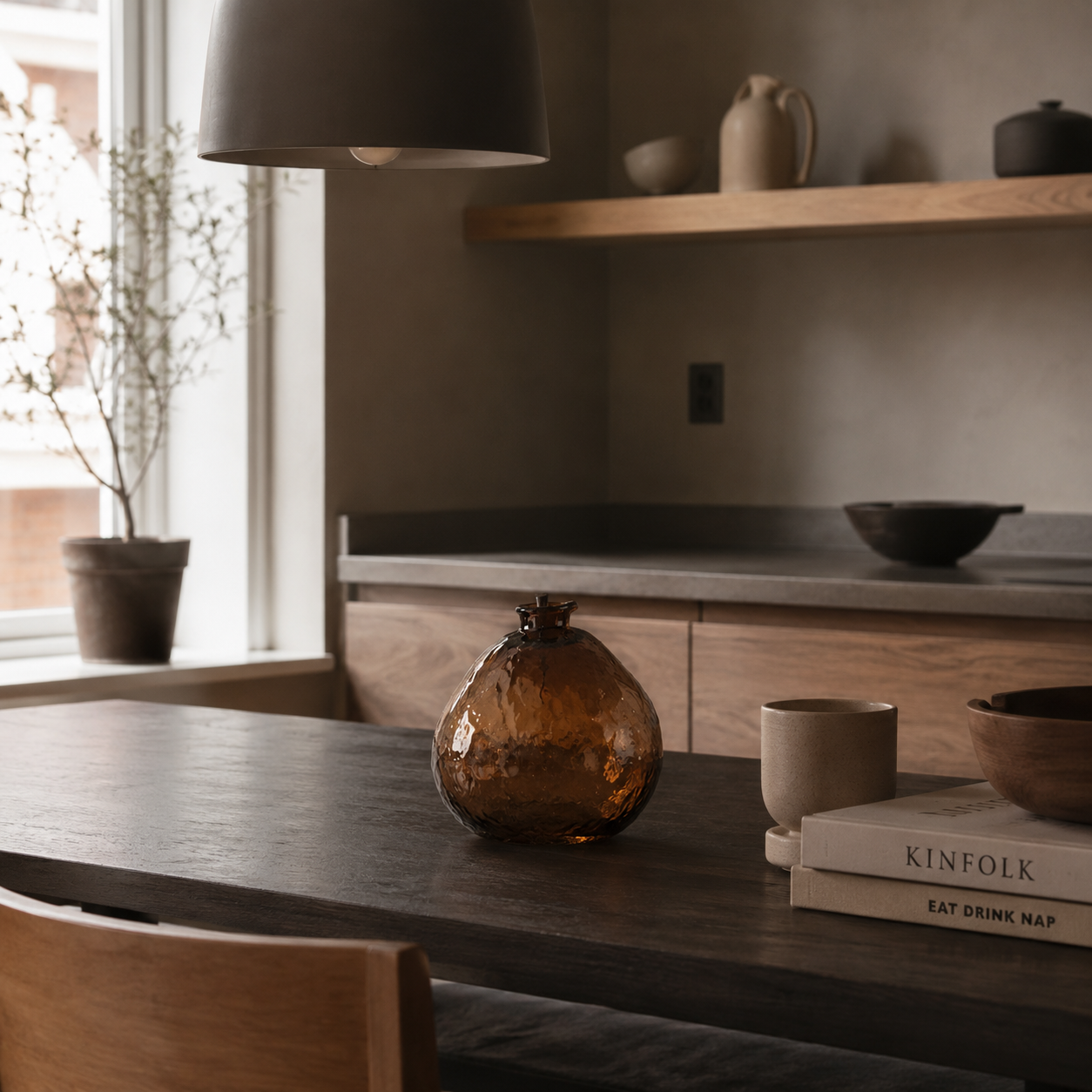 Stor rund vase i glass på et bord i et moderne kjøkken.