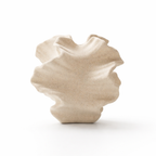 Liten vase i beige laget av keramikk i et hvitt studio. 