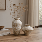 To keramikkvasere i ulike størrelser med tørkede blomster på spisebord, Kinfolk-bøker og naturlig lys fra vindu